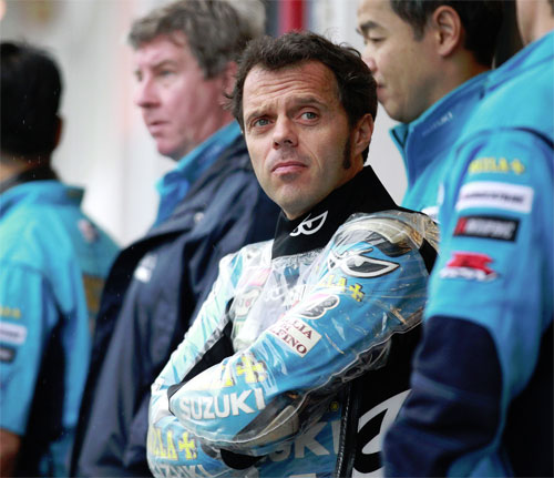 Loris Capirossi studys the rain in Estoril